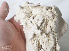 a hand is holding a piece of white food that looks like something out of the ground