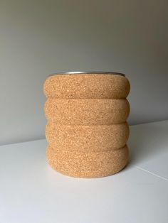 a close up of a cork container on a table with a white background and grey wall behind it