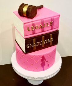 a three tiered cake decorated with books and a judge's gaven on top