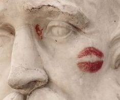 the face of a statue with red lipstick on it