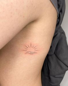 a woman's arm with a small sun tattoo on the back of her shoulder