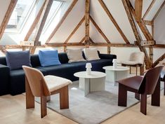 a living room filled with lots of furniture next to a large window and wooden beams