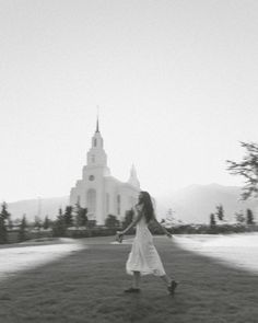 a woman is walking in front of a church