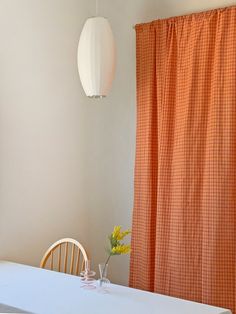 a dining room table and chairs with an orange checkered curtain