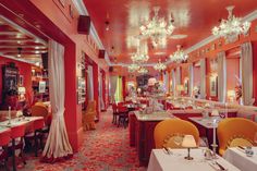 a restaurant with red walls and chandeliers hanging from the ceiling