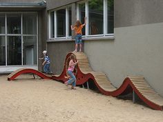 children are playing on a slide in the sand