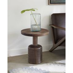 a vase with a plant in it sitting on a small table next to a chair