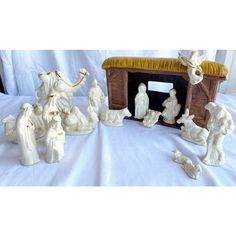 some white figurines are sitting on a bed with a nativity scene in the background