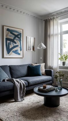 a living room with a couch, coffee table and rug on the floor in front of a window