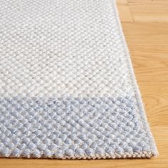 a white and blue rug sitting on top of a wooden floor next to a hard wood floor