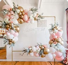 a bride to be sign with balloons and greenery on the wall behind it in front of a pink backdrop