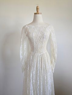 a white lace dress on a mannequin dummy with long sleeves and an open back