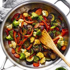 a pan filled with vegetables and a wooden spoon