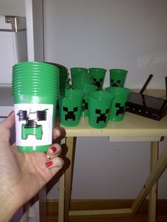 a person holding a cup with green cups on it and some other cups in front of them