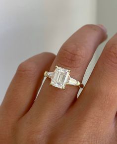 a woman's hand with an engagement ring and diamond baguette on it