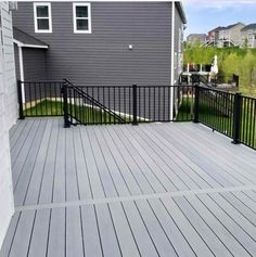 a deck with black iron railings next to a gray house