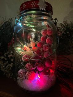 a glass jar filled with christmas decorations on top of a table