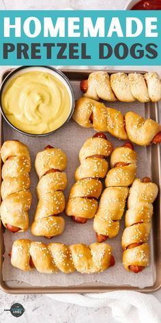 homemade pretzel dogs on a baking sheet with mustard and ketchup in the background