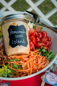 a bowl filled with carrots, lettuce and tomatoes next to a jar of homemade food