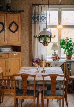 a dining room table and chairs in front of a window with potted plants on it