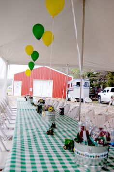 a green and white checkered table cloth with yellow and green balloons hanging from it