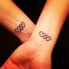 two people with matching tattoos on their wrists are holding each other's hands