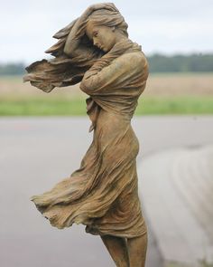 a statue of a woman with her hair blowing in the wind on a cement block