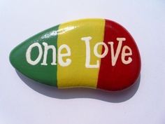 a rock with the word one love painted on it, sitting on a white surface