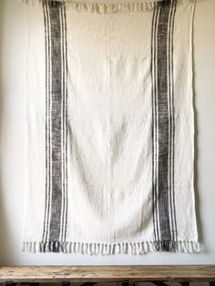 a black and white striped towel hanging on a wall next to a wooden table with a bench in front of it