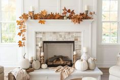 a living room filled with furniture and a fire place covered in fall leaves on top of a mantle