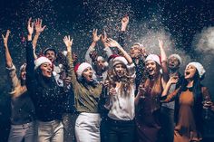 a group of people celebrating with confetti in the air and wearing santa hats