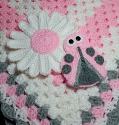 a crocheted blanket with a ladybug and flower on it