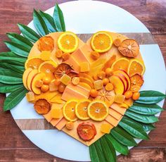 a heart shaped platter filled with oranges and other fruits