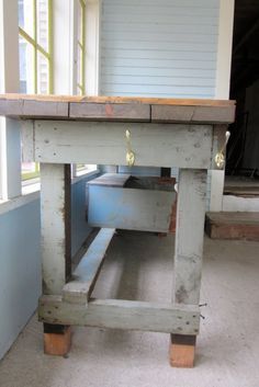 an old wooden table with drawers underneath it in the middle of a room next to a window