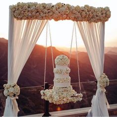 the wedding cake is on display at the top of the hill with white draping