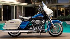 a blue and white motorcycle parked in front of a house next to a swimming pool