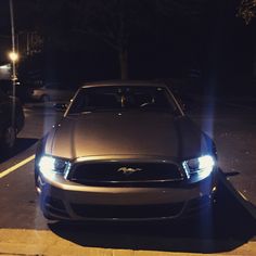 a car is parked in the parking lot with its headlights turned on at night time