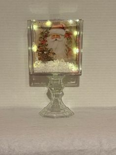 a small glass block with a santa clause on it's face and lights in the background