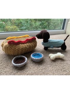 crocheted toy dog and food set on carpet next to window