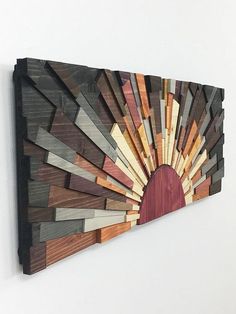 a wooden wall hanging with many different colored wood pieces on it's sides and a circular hole in the middle