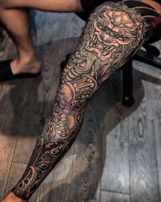 a man's leg covered in black and grey ink with an intricate dragon tattoo on it