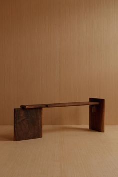 a wooden bench sitting on top of a hard wood floor next to a brown wall