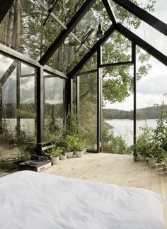 a bed sitting inside of a bedroom next to a window filled with plants and trees