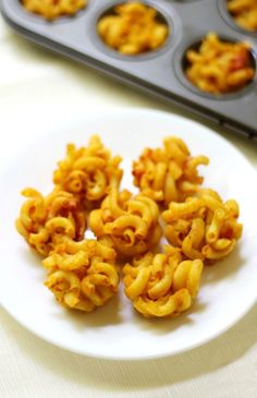 macaroni and cheese on a white plate next to muffin tins in the background