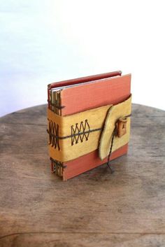 an old book is sitting on top of a wooden table with a string attached to it