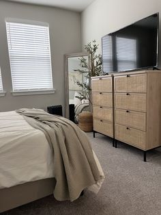 a bedroom with a bed, dresser and television on the stand in front of it