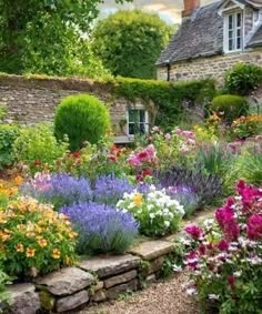 a garden filled with lots of flowers next to a stone wall