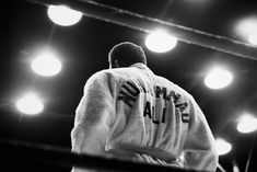 a man standing in front of a stage with lights on the ceiling and his jacket draped over his shoulders