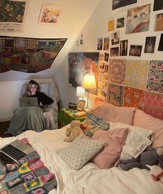 a woman is sitting on her bed using a laptop