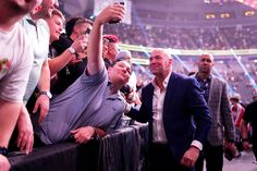 a man taking a selfie with his cell phone in front of an audience at a sporting event